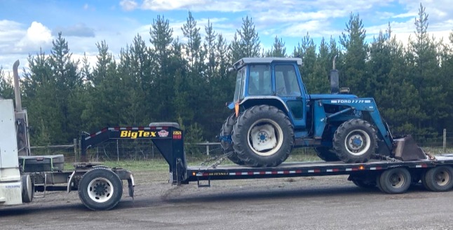 Tractor being hauled by Short Acres Trucking